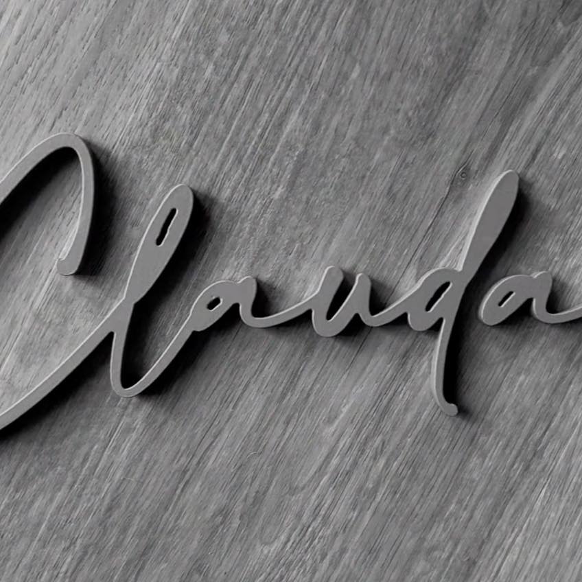 Grey aluminium house sign in a handwritten script font mounted on grey timber cladding